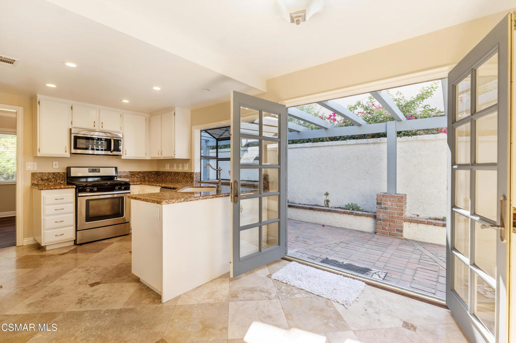 932 Thistlegate Road Oak Park, CA 91377 - Photo 9 of 25 a kitchen with stainless steel appliances kitchen island granite countertop a refrigerator and a stove top oven