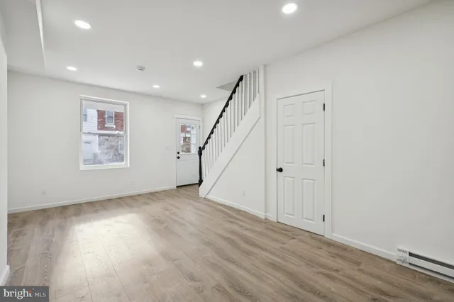 a view of an empty room with wooden floor and stairs