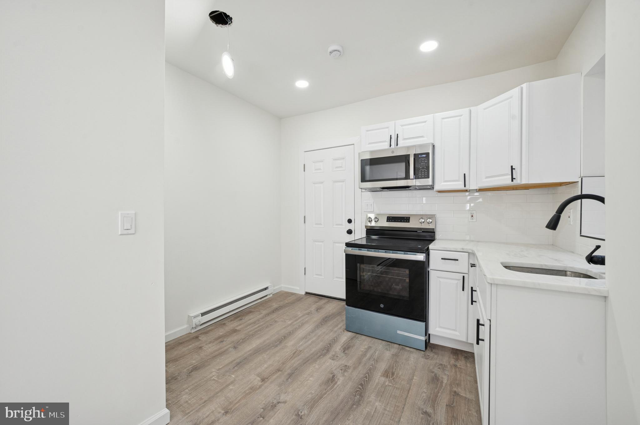 5929 Spring Street Philadelphia, PA 19139 - Photo 9 of 15 a kitchen with granite countertop white cabinets and stainless steel appliances