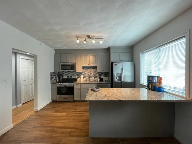 a large kitchen with a large counter top stainless steel appliances and cabinets