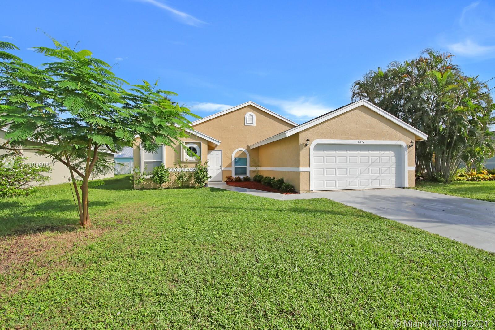 6247 Robinson Street Jupiter, FL 33458 - Photo 3 of 56 a front view of a house with a yard and garage