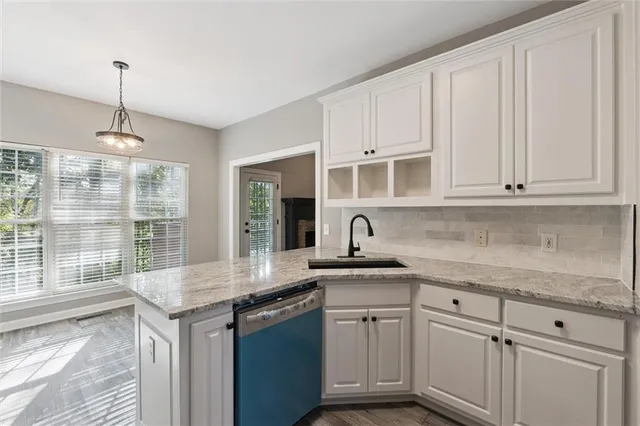 a kitchen with stainless steel appliances granite countertop a sink a stove and white cabinets