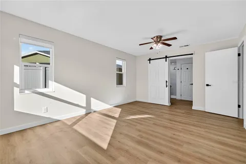 a view of empty room with wooden floor and fan