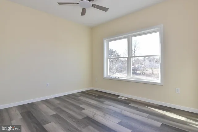 an empty room with a window and ceiling fan