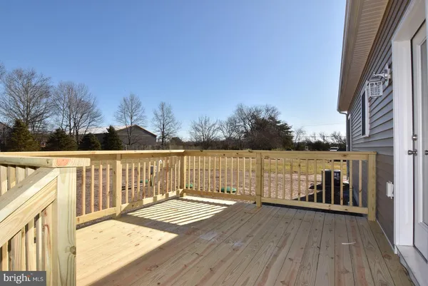 a view of a balcony with wooden floor and fence next to a yard
