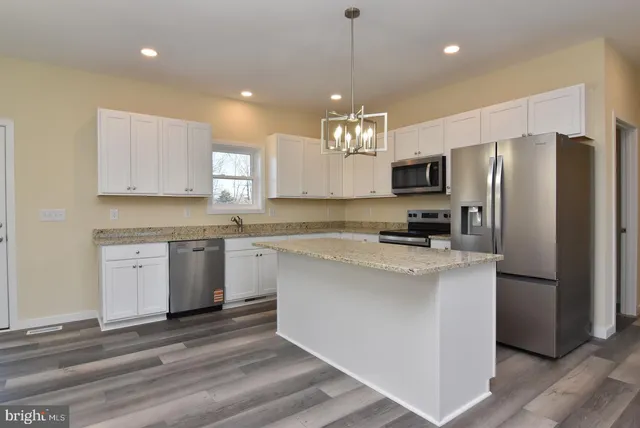 a kitchen with kitchen island granite countertop stainless steel appliances cabinets a sink and a counter top space