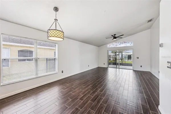 a view of empty room with wooden floor and chandelier