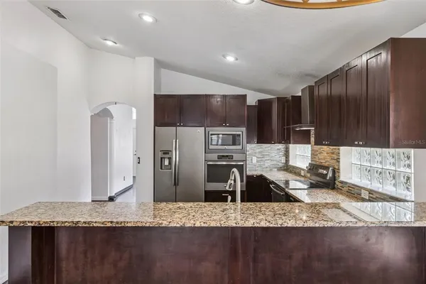 a kitchen with stainless steel appliances granite countertop a sink refrigerator and microwave
