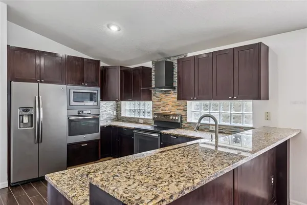 a kitchen with stainless steel appliances granite countertop a sink refrigerator and cabinets
