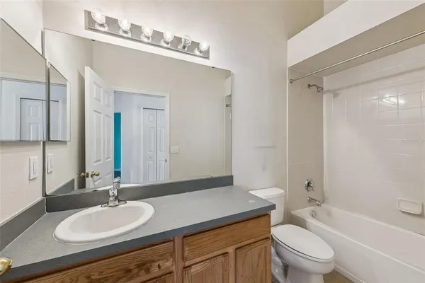 a bathroom with a granite countertop sink toilet a large mirror a bathtub and shower