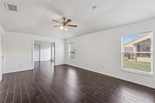 a view of an empty room with a window and wooden floor