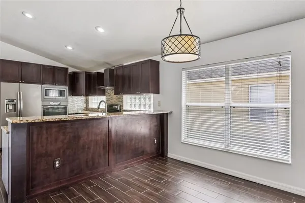 a kitchen with kitchen island granite countertop a stove a refrigerator a sink and a dishwasher with wooden floor