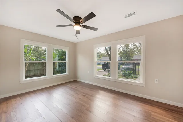 a view of an empty room with wooden floor and a window