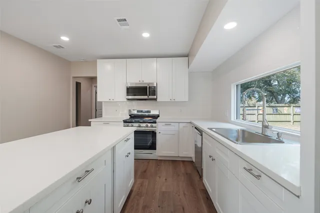a kitchen with sink a microwave and cabinets