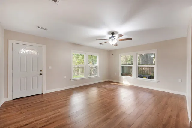 a view of an empty room with wooden floor and a window