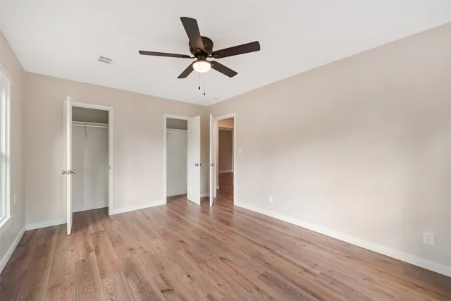 a view of a big room with wooden floor a ceiling fan and staircase