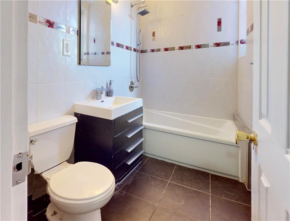 2909 Ocean Avenue, Unit 4E Brooklyn, NY 11235 - Photo 7 of 10 a bathroom with a sink a toilet and a mirror