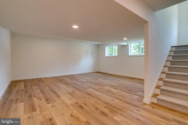 an empty room with wooden floor fireplace and windows
