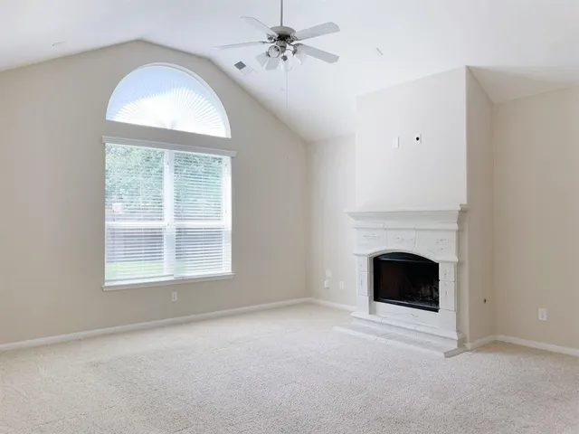 an empty room with chandelier windows and fireplace