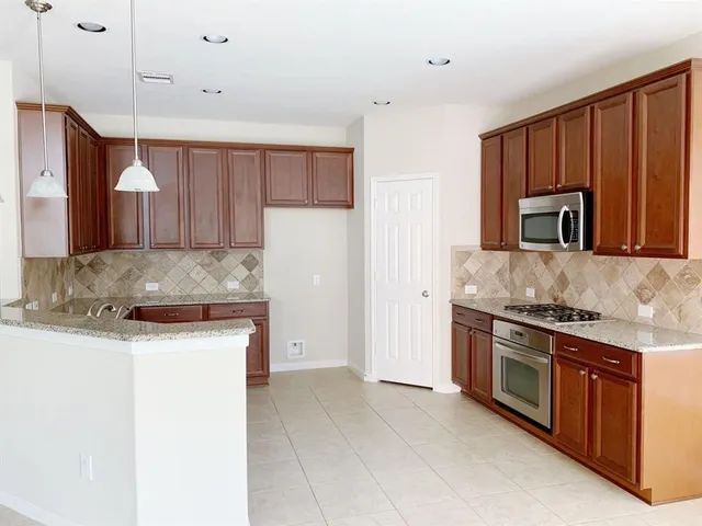 a kitchen with stainless steel appliances granite countertop a stove a sink and a refrigerator