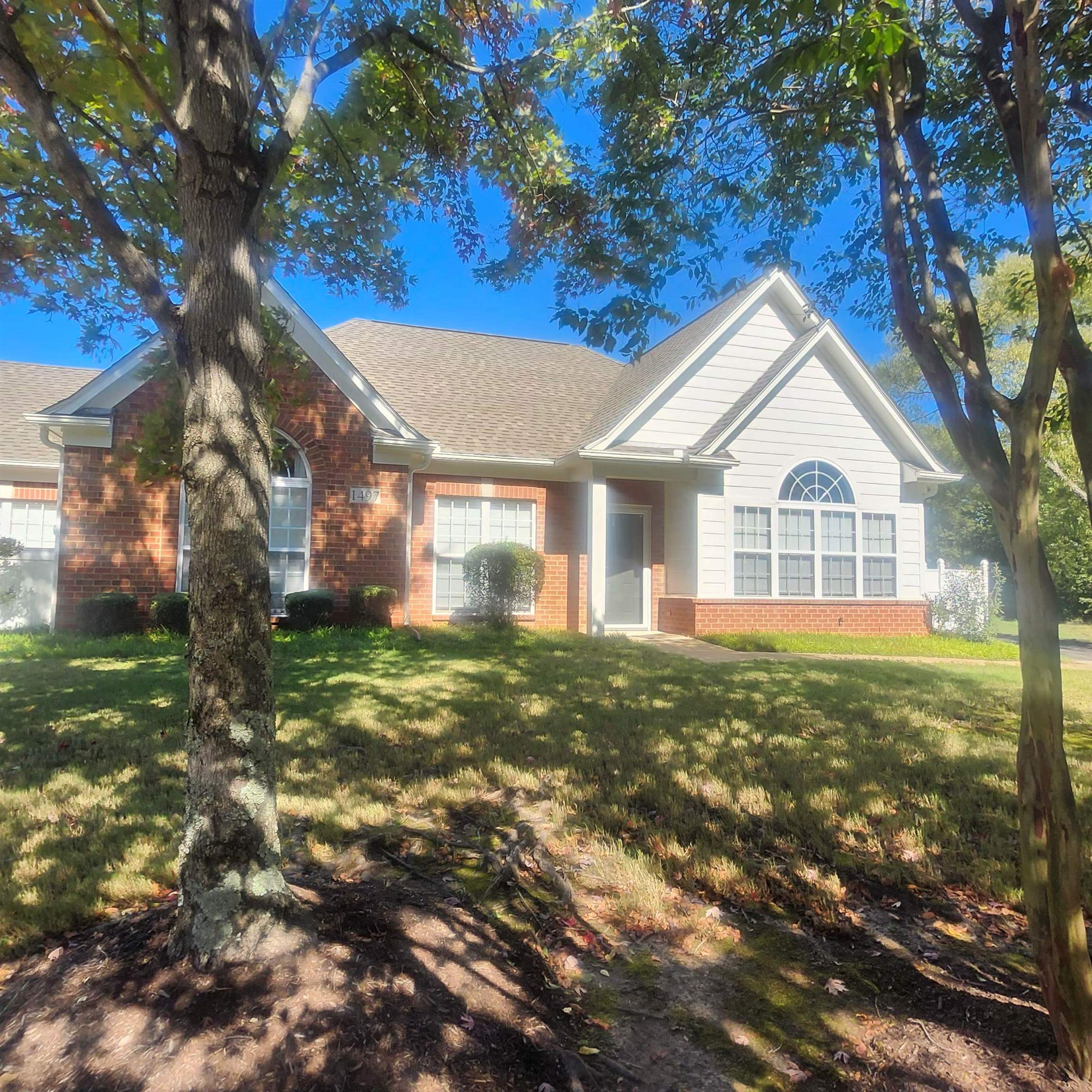 View of front of home with brick siding, a front lawn, and a shingled roof