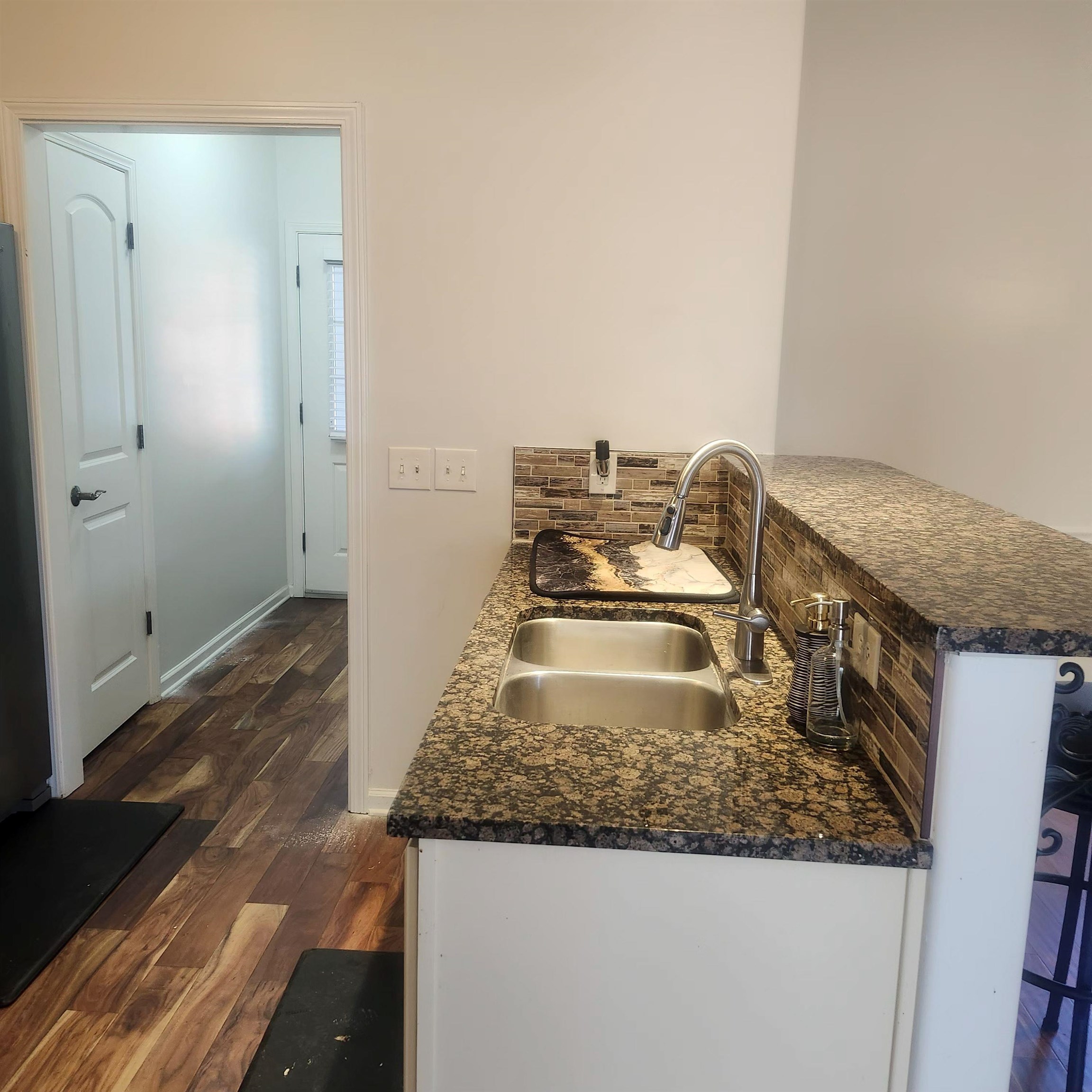 1497 Castle Pines Circle, Unit 18 Collierville, TN 38017 - Photo 19 of 23 Kitchen featuring dark wood-type flooring, a peninsula, dark stone countertops, and backsplash