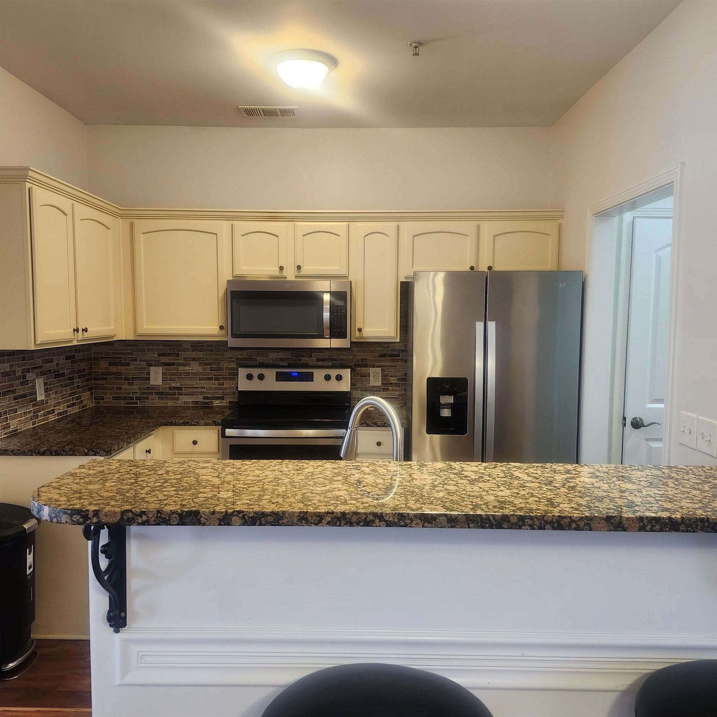 1497 Castle Pines Circle, Unit 18 Collierville, TN 38017 - Photo 5 of 23 Kitchen featuring stainless steel appliances, tasteful backsplash, cream cabinets, and dark stone countertops