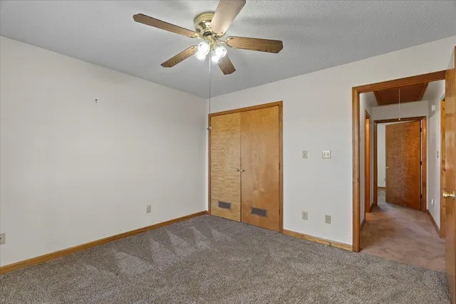 an empty room with closet and a ceiling fan
