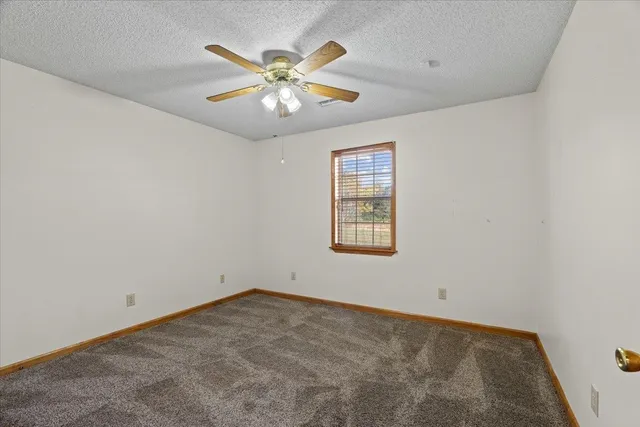 an empty room with windows and chandelier fan