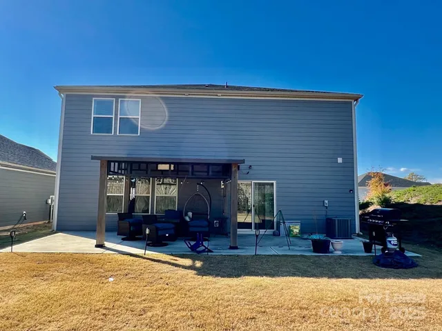a view of a house with a barbeque grill and a yard