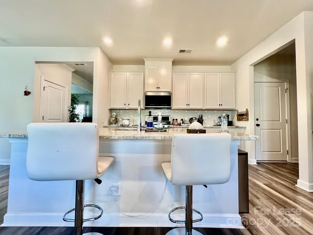 a living room with stainless steel appliances furniture and a kitchen view