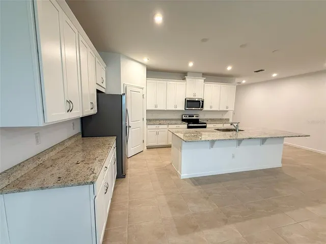 a large kitchen with stainless steel appliances granite countertop a granite counter tops and a stove