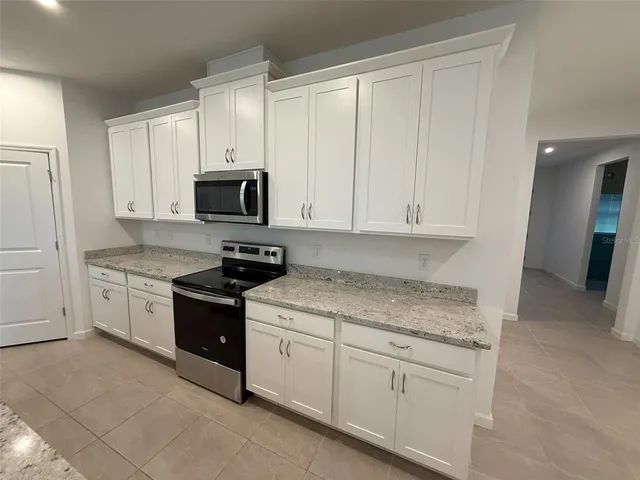 a kitchen with granite countertop white cabinets and stainless steel appliances