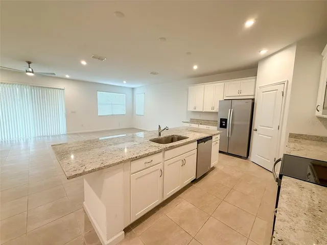 a large kitchen with stainless steel appliances granite countertop a sink and a refrigerator