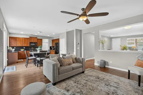 a living room with furniture kitchen view and a wooden floor