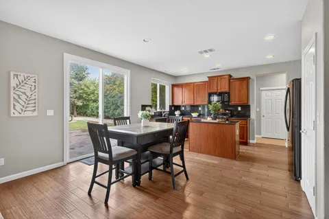 a kitchen with stainless steel appliances granite countertop a kitchen island hardwood floor sink stove dining table and chairs