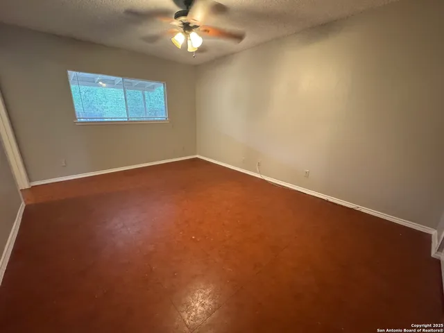 an empty room with windows and fan