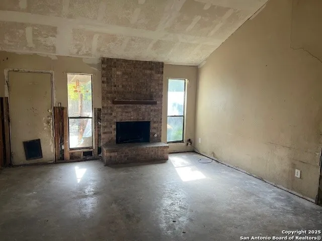 an empty room with windows and fireplace