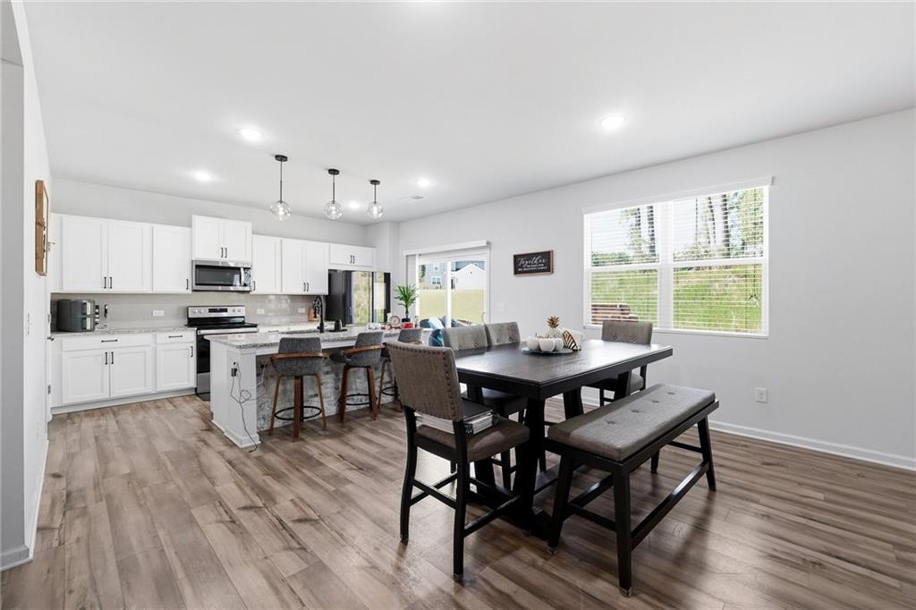 620 Cayenne Way Lawrenceville, GA 30045 - Photo 8 of 25 a open dining room with kitchen island stainless steel appliances wooden floor dining table and chairs