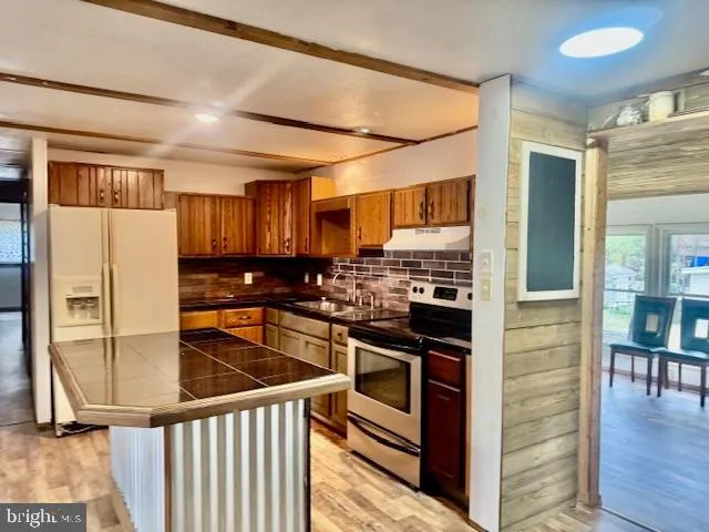 a kitchen with stainless steel appliances granite countertop a stove a sink and a refrigerator