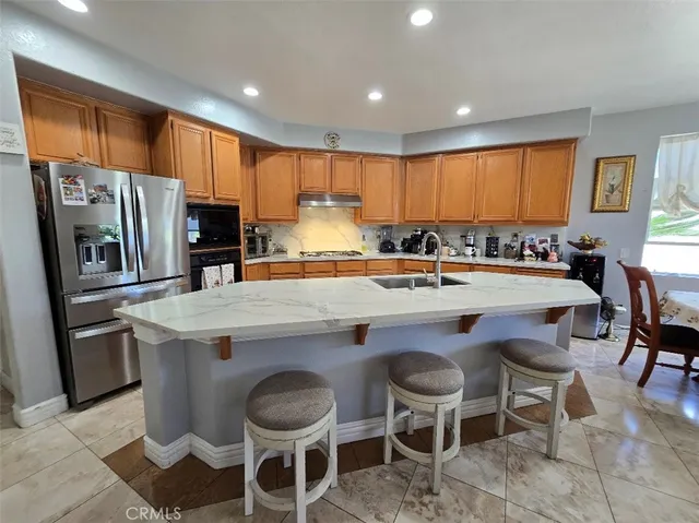 a kitchen with stainless steel appliances granite countertop a table chairs sink refrigerator and microwave