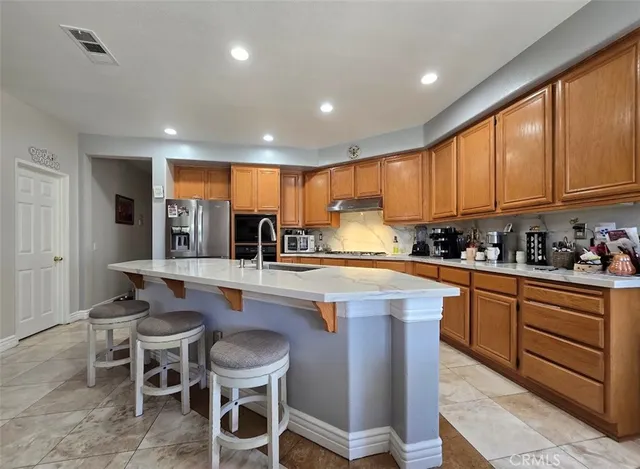 a kitchen with kitchen island granite countertop wooden cabinets and white stainless steel appliances