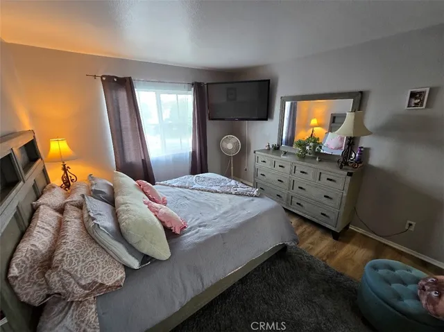 a bedroom with a bed and flat tv screen on dresser