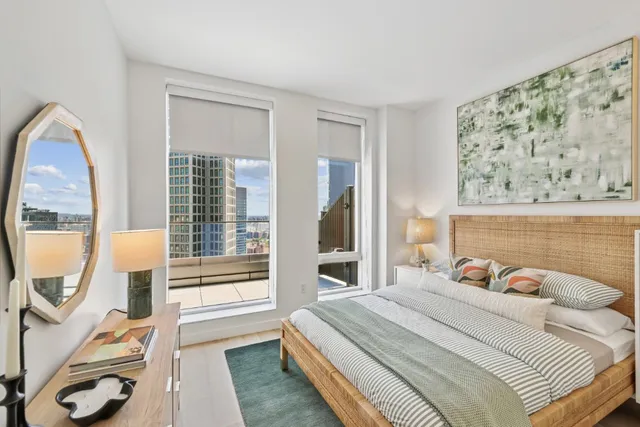 a bedroom with a bed and a large mirror next to a window