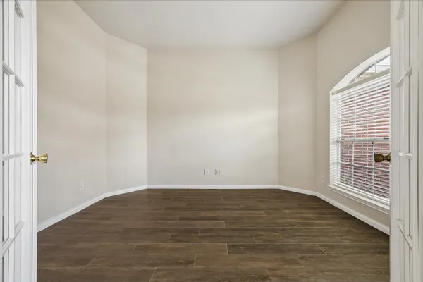 a view of an empty room with wooden floor and a window