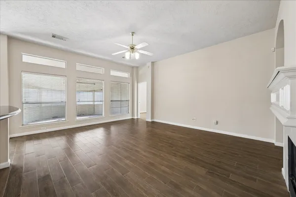 an empty room with wooden floor chandelier and windows