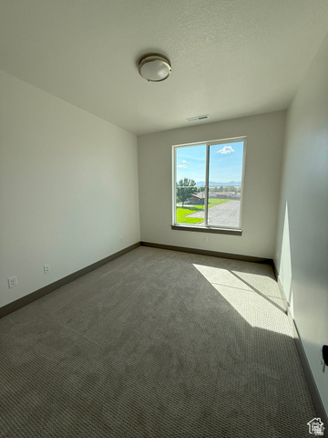 8087 South 615 East, Unit 3 Sandy, UT 84070 - Photo 16 of 23 Light-filled interior space featuring a large window, textured carpeting, neutral wall finishes, a flush-mount ceiling light fixture, and dark baseboards