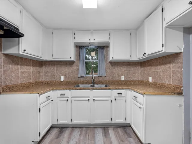 a kitchen with white cabinets sink and dishwasher