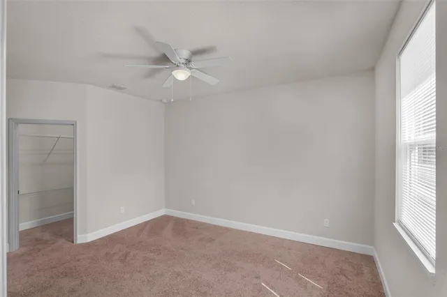 an empty room with a window and a fan