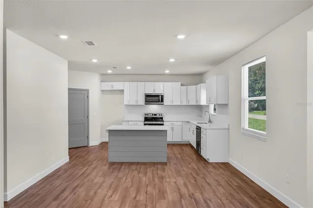 a view of kitchen with wooden floor and electronic appliances